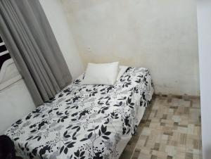 ein Bett mit einer schwarzen und weißen Bettdecke in einem Zimmer in der Unterkunft Casa em Milagres in São Miguel dos Milagres