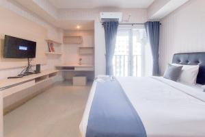 a bedroom with a large bed and a tv at Cozy Living Studio at Paramount Skyline Apartment By Travelio in Tangerang