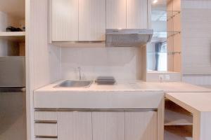 a kitchen with white cabinets and a sink at Cozy Living Studio at Paramount Skyline Apartment By Travelio in Tangerang