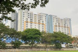 a large apartment building with trees in front of it at Cozy Living Studio at Paramount Skyline Apartment By Travelio in Tangerang
