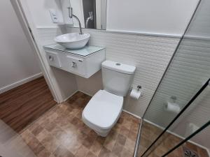 a bathroom with a white toilet and a sink at Studio tipuana, varandinha aberta com rede in Brasilia