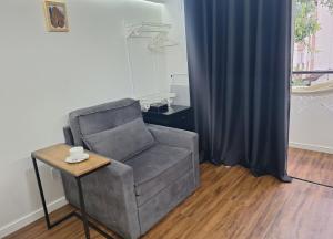 a chair and a table in a room with a curtain at Studio tipuana, varandinha aberta com rede in Brasilia