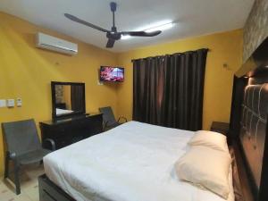 ein Schlafzimmer mit einem Bett und einem Stuhl und einem Fernseher in der Unterkunft Departamento cerca de hospitales in Campeche