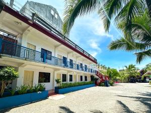 a building with blue balconies and palm trees at Lotus Sun & Waves Beach Resort in Baler