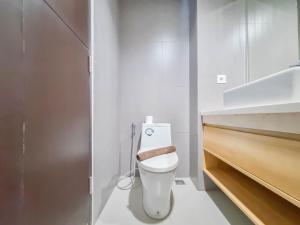 a white bathroom with a toilet and a sink at Homey and Minimalist Studio at Patraland Amarta Apartment By Travelio in Kejayan +9 photos