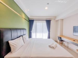 a bedroom with a bed with two towels on it at Homey and Minimalist Studio at Patraland Amarta Apartment By Travelio in Kejayan