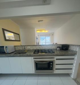 una cucina con lavello e fornello forno superiore di Cond Twice Guaruja Sp a Guarujá