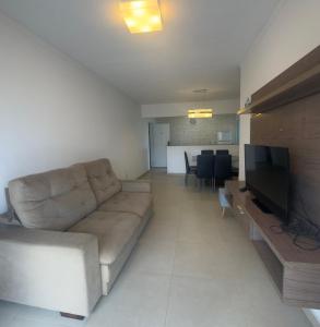 un soggiorno con un divano e una televisione di Cond Twice Guaruja Sp a Guarujá Altre 16 foto