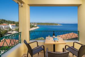 a balcony with a table and chairs and a view of the ocean at Stella Hotel Apartments in Fiskardo