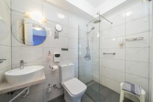 a white bathroom with a toilet and a sink at Stella Hotel Apartments in Fiskardo