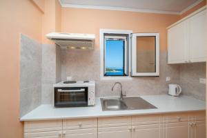 a kitchen with a sink and a microwave at Stella Hotel Apartments in Fiskardo