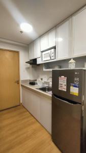 a kitchen with white cabinets and a black refrigerator at Golden Stay Trees Residences Novaliches Quezon City in Manila +13 photos