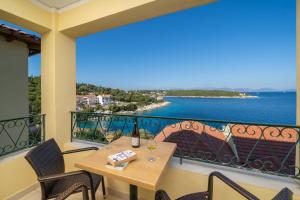 a balcony with a table and chairs and a view of the ocean at Stella Hotel Apartments in Fiskardo
