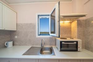 a kitchen with a sink and a microwave at Stella Hotel Apartments in Fiskardo +37 photos
