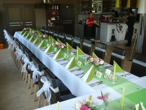 une grande table avec des tables blanches, des chaises et des fleurs dans l'établissement Toscca, à Čelákovice