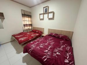 two beds in a bedroom with red comforter at Family Stay at Quintet A3A-3A-6 in Tanah Rata