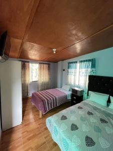 a bedroom with two beds and a tv in it at Hostal Sol de Chosica in Chosica