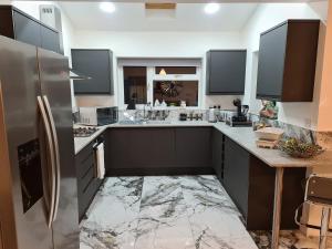 a kitchen with black cabinets and a stainless steel refrigerator at SAV Stays 5 Bed Luxury Detached House in Leicester in Humberstone
