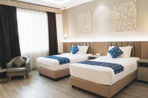 a hotel room with two beds and a chair at Batam Harbour Boutique Hotel & Spa in Nagoya