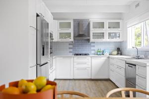 a kitchen with white cabinets and a table with a bowl of fruit at Seaview Dromana - where the mountain meets the sea in Dromana