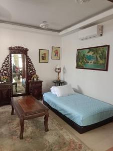 Un dormitorio con una cama, una mesa y un espejo. en Villa Medina 12 pax private bungalow at Pantai Bagan Lalang, en Tanjong Sepat