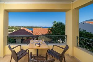 a patio with a table and chairs on a balcony at Stella Hotel Apartments in Fiskardo