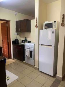 a kitchen with a white refrigerator and a microwave at Golf in Kiambu