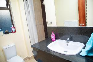 a bathroom with a sink and a toilet and a mirror at Golf in Kiambu +26 photos