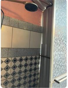 y baño con ducha y azulejos blancos y negros. en Quarto de Pedra, en Cuiabá