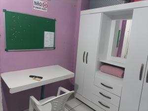 una habitación con un escritorio blanco y una pizarra en Quarto de Pedra, en Cuiabá 2 fotos más