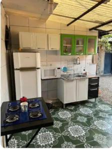 una pequeña cocina con armarios verdes y una mesa en Quarto de Pedra, en Cuiabá