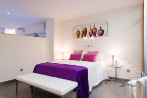1 dormitorio con 1 cama blanca con manta morada en Suites Garden Loft El Greco, en Las Palmas de Gran Canaria