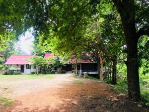 a house with a red roof and a dirt road at LungYod Guest House in Ban Tha Ling Lom