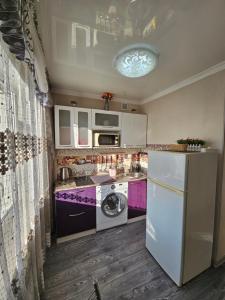 a kitchen with a white refrigerator and a dishwasher at Lux Apartment on Mayakovsky 6 in Ustʼ-Kamenogorsk