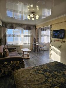 a living room with a couch and a table and windows at Lux Apartment on Mayakovsky 6 in Ustʼ-Kamenogorsk