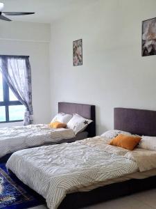 two beds sitting next to each other in a bedroom at Aura Homestay - Edusphere Suites in Cyberjaya
