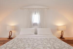a bedroom with a white bed with two lamps at Orabel Suites Santorini (Adults Only) in Perivolos