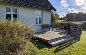 a wooden deck with two chairs on a house at Two-Bedroom Holiday Home In Gudhjem in Gudhjem +8 photos