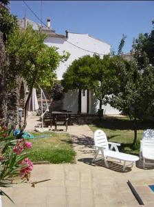 eine Terrasse mit zwei weißen Stühlen, einem Tisch und Bäumen in der Unterkunft Cortijo Retarta Jubrique in Jubrique
