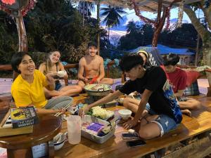 a group of people sitting around a table eating food at Baan Klong House in Baan Khai