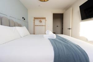 a bedroom with a large white bed and a television at Cohost Partners Albert Hall 3 min to City Centre in Swansea +269 photos