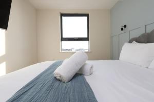 a bedroom with a white bed with towels on it at Cohost Partners Albert Hall 3 min to City Centre in Swansea