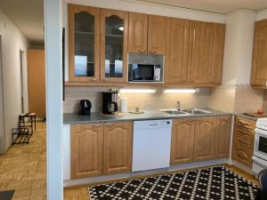 a kitchen with wooden cabinets and a white dishwasher at Cozy 2BR Apartment KA64 with sauna in Oulu