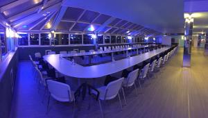 a long table and chairs in a room with blue lights at Hotel Verdi in Vicenza