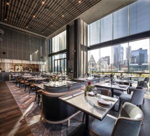 墨尔本voco Melbourne Central的有桌椅和大窗户的餐厅