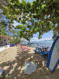a group of picnic tables and a surfboard on the beach at Secret Garden Family House in Ko Chang
