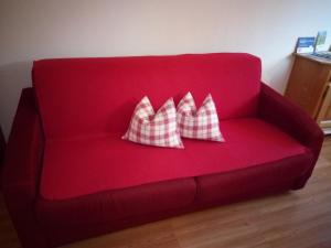 a red couch with two pillows on it at Trogerhof in Dobbiaco