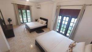 a room with two beds and a couch and windows at Honey Dew Villa Minuwangoda in Balabowa