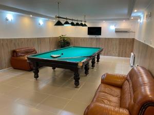 a pool table in a room with two couches and a tv at Apec Hotel in Atyrau