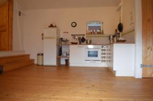 a kitchen with white appliances and a wooden floor at Himmel&Erden in Nordleda